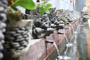 a row of water fountains on a brick wall at Giri Sari Guest House Pemuteran Bali in Pemuteran