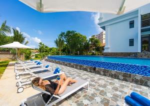 a woman laying on lounge chairs next to a swimming pool at Homestead Seaview Phú Quốc Hotel in Phú Quốc