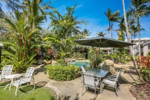 a patio with a table and chairs and an umbrella at Melaleuca Resort in Palm Cove
