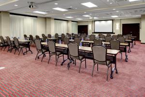 Hyatt Place Richmond Airport في ريتشموند: قاعة اجتماعات مع طاولات وكراسي وشاشة