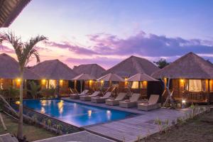 a resort with a swimming pool with chairs and umbrellas at Lembongan Mantra Huts - CHSE Certified in Nusa Lembongan