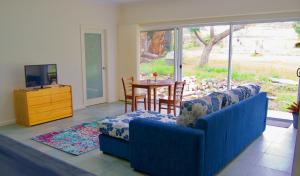 Sala de estar con 2 sillas azules, mesa y TV en Back Valley Farmstay Bed and Breakfast, en Victor Harbor