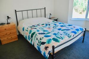 Back Valley Farmstay Bed and Breakfast في فيكتور هاربور: غرفة نوم بسرير وبطانية زرقاء وبيضاء