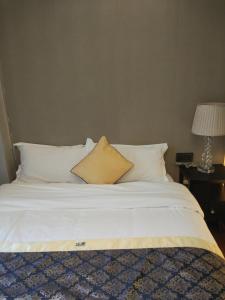 Una cama con sábanas blancas y una almohada. en River Image Boutique Apartment en Shenzhen