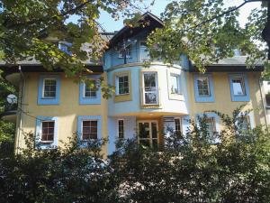 une grande maison jaune avec des fenêtres bleues et des arbres dans l'établissement Zielone Studio, à Oborniki Śląskie