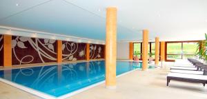 a large swimming pool in a building with chairs at Hotel Sonnalp in Kirchberg in Tirol