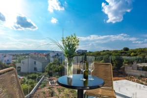 a table with two wine glasses and flowers on a balcony at Pansion Leggero in Krk