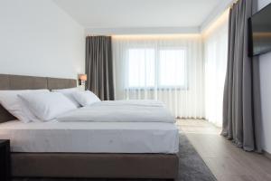 a bedroom with a white bed and a large window at Pansion Leggero in Krk