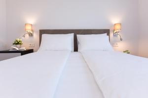a bedroom with a large white bed with two lamps at Pansion Leggero in Krk