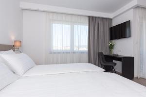 a bedroom with two beds and a desk and a television at Pansion Leggero in Krk