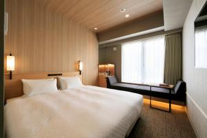 a bedroom with a large white bed and a window at Candeo Hotels Kobe Tor Road in Kobe