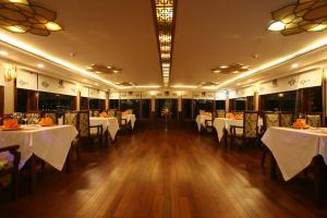 un comedor con mesas y sillas blancas en Oriental Sails Cruise, en Ha Long