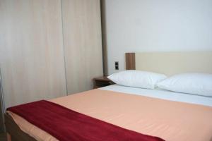 a bedroom with a bed with a red blanket on it at Lucija Apartments in Krk