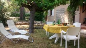 une table et des chaises sous un arbre dans une cour dans l'établissement Maison Charrasse, à Flassan