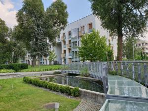 a garden with a bridge over a pond in front of a building at Apartament Marina Mokotów in Warsaw