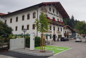 ein großes weißes Gebäude mit einem Baum davor in der Unterkunft Hotel Alte Post in Siegsdorf