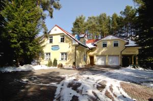 ジェロナ・グラにあるHotelik Gościniec Pod Sosnami Drzonkówの地面雪黄色い家