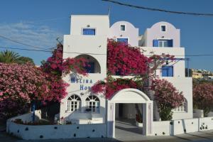 um edifício branco com flores cor-de-rosa em Melina Hotel em Fira