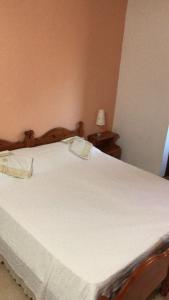 Agriturismo S'Armidda في Seùlo: غرفة نوم بسرير ابيض كبير مع طاولتين
