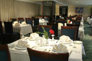 a dining room with white tables and chairs with white napkins at Surmeli Adana Hotel in Adana