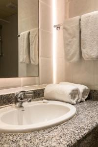 a bathroom with a sink and a mirror and towels at Mayfair Gardens in Paphos