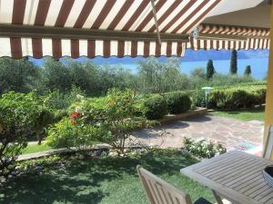 eine Terrasse mit Sonnenschirm, Tisch und Stühlen in der Unterkunft Sander House in Malcesine