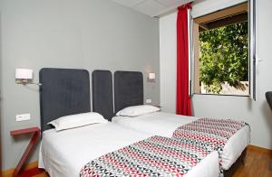 two beds sitting next to each other in a room at Hôtel Méditerranée in Calvi