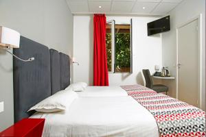 a bedroom with a white bed with a red curtain at Hôtel Méditerranée in Calvi