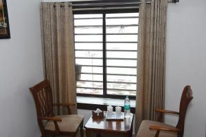 une chambre avec une table, deux chaises et une fenêtre dans l'établissement Alakhnanda Guest House, à Varanasi