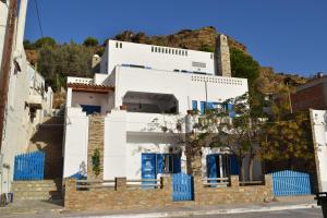 una casa bianca su una collina con porte blu di CLIO'S BEACH HOUSE - DELUXE BEACH FRONT PROPERTY a Órmos