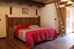 ein Schlafzimmer mit einem Bett mit einer roten Decke und einer Leiter in der Unterkunft Maison Chenal in Montjovet