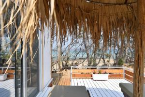 a patio with a view of the ocean from a straw roof at Surfing Beach Village Paros in Santa Maria