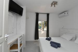 a white bedroom with a bed and a desk at Surfing Beach Village Paros in Santa Maria