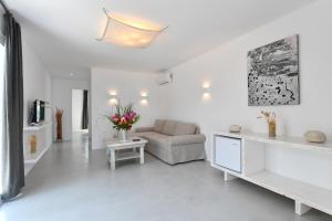 a white living room with a couch and a table at Surfing Beach Village Paros in Santa Maria