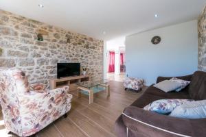 a living room with two couches and a stone wall at Villa Dundo Pero in Babino Polje