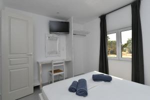 a bedroom with a bed with two blue towels on it at Surfing Beach Village Paros in Santa Maria