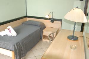 a bedroom with a bed and a lamp on a table at Hotel Gran Delta in Rosolina