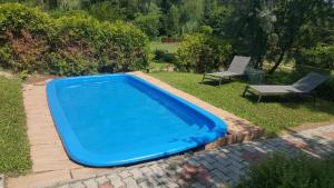 a blue swimming pool in a yard with a chair at Joó House in Balatonfüred