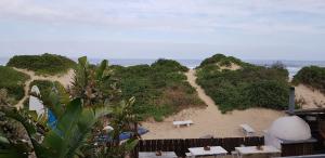 a view of a beach with benches and the ocean at Pili Pili Beach Cabanas in Sedgefield