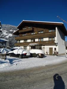 a person taking a picture of a building with snow covered cars at Gästehaus Birkenheim in Zell am Ziller