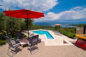 a patio with a red umbrella and a swimming pool at Holiday House Rosalia With Seaview And Swimming Pool in Sužan
