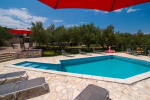 a swimming pool with chairs and an umbrella at Holiday House Rosalia With Seaview And Swimming Pool in Sužan