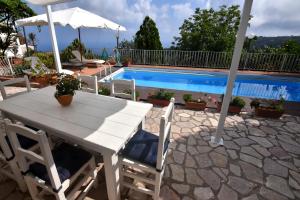 Biały stół z krzesłami i parasol przy basenie w obiekcie Villa Asia Holiday Home w mieście SantʼAgata sui Due Golfi