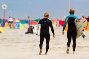 deux hommes marchant sur la plage avec leurs planches de surf dans l'établissement Hotel Domburg4you, à Domburg