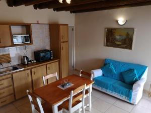 un salon avec une table et un canapé bleu dans l'établissement Kassiesbaai Cottage, à Arniston 8 autres photos