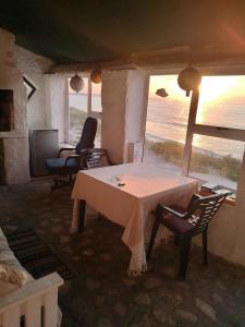 Cette chambre dispose d'une table et de chaises et offre une vue sur l'océan. dans l'établissement Kassiesbaai Cottage, à Arniston