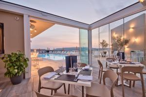 a restaurant with tables and chairs and a pool at Luna Holiday Complex in Mellieħa