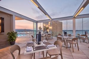 a restaurant with tables and chairs and a view of the ocean at Luna Holiday Complex in Mellieħa