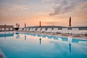 a large swimming pool with chairs and umbrellas at Luna Holiday Complex in Mellieħa