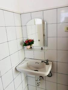 een wit betegelde badkamer met een wastafel en een spiegel bij Srjo Fun Central Resort in Calamba
